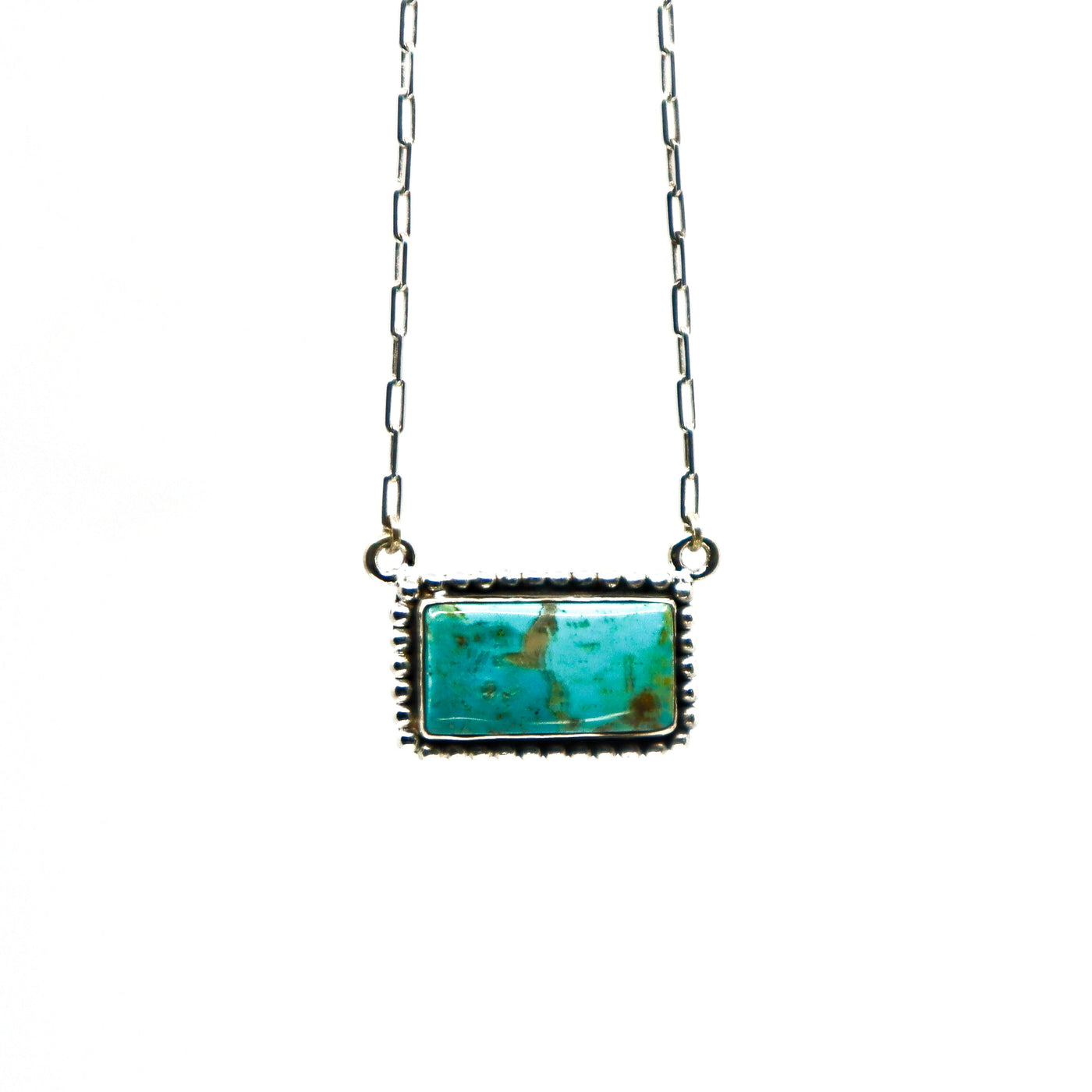 Handmade sterling silver necklace with large rectangular turquoise stone and intricate border design