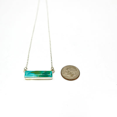Handmade sterling silver necklace with a large turquoise bar pendant next to a dime for size comparison