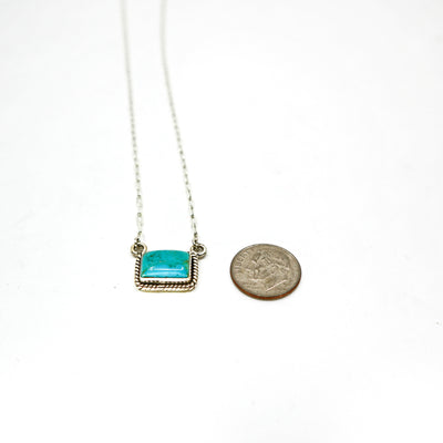 Handmade woven border sterling silver necklace with turquoise bar pendant next to a dime for size comparison