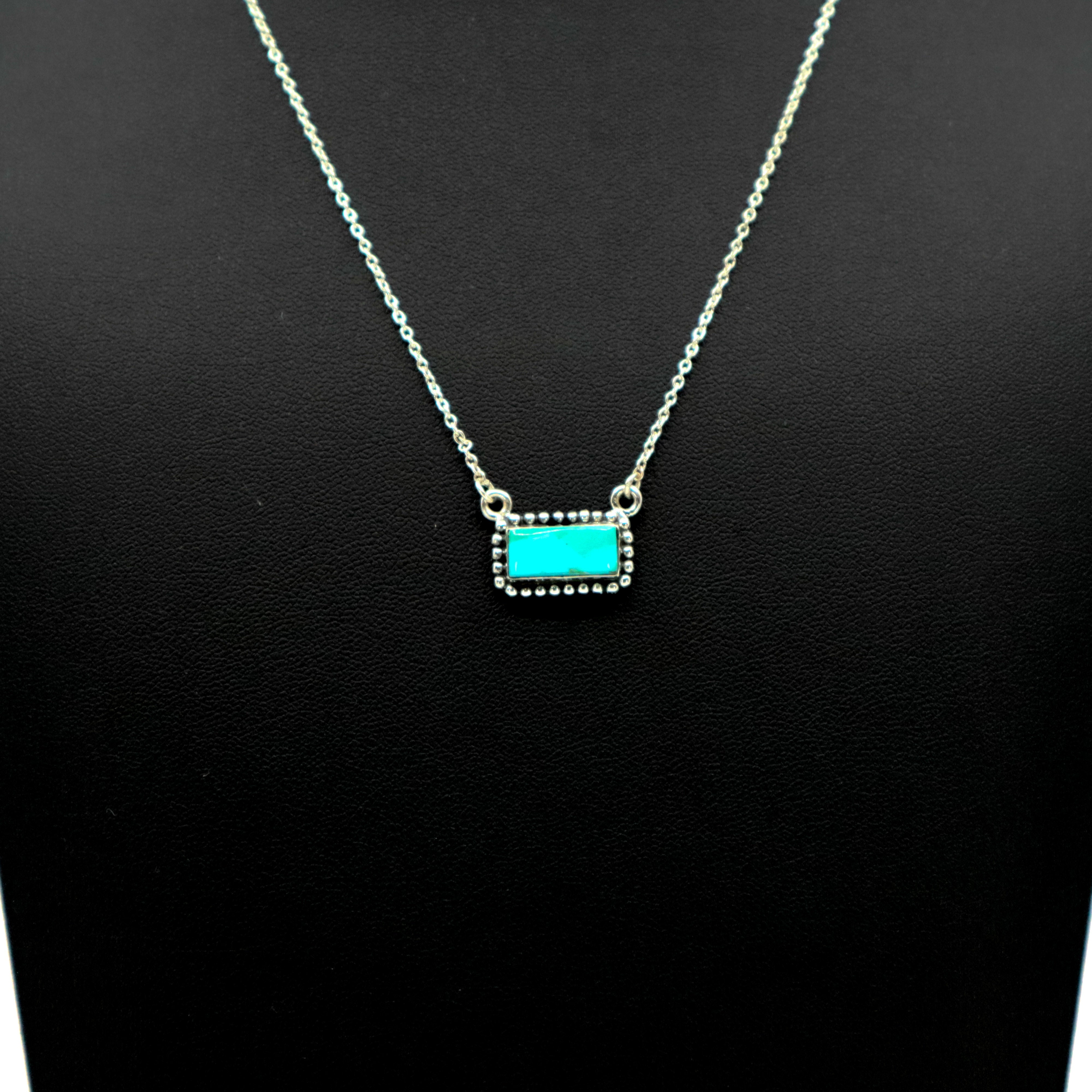 Sterling silver necklace with intricate border and small turquoise bar pendant