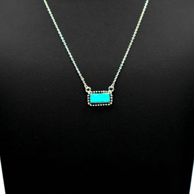 Sterling silver necklace with intricate border and small turquoise bar pendant