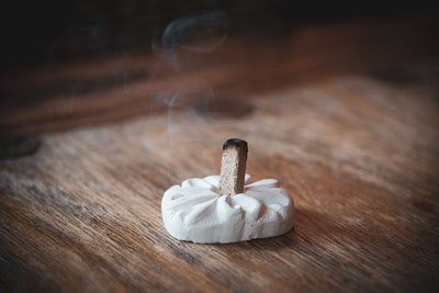 Wood incense brick on holder with gentle smoke rising.