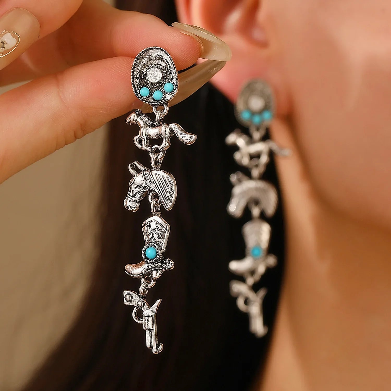 Close-up of Western Boho Earrings featuring silver cowboy-themed charms and turquoise stones worn on ear