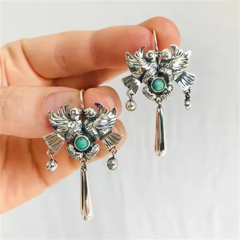 Vintage styled silver-tone earrings with turquoise stone, bird and flower design.