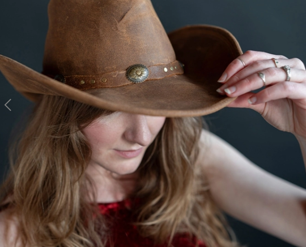 Woman wearing Silverton Dude Hat in brown leather with decorative metal hatband