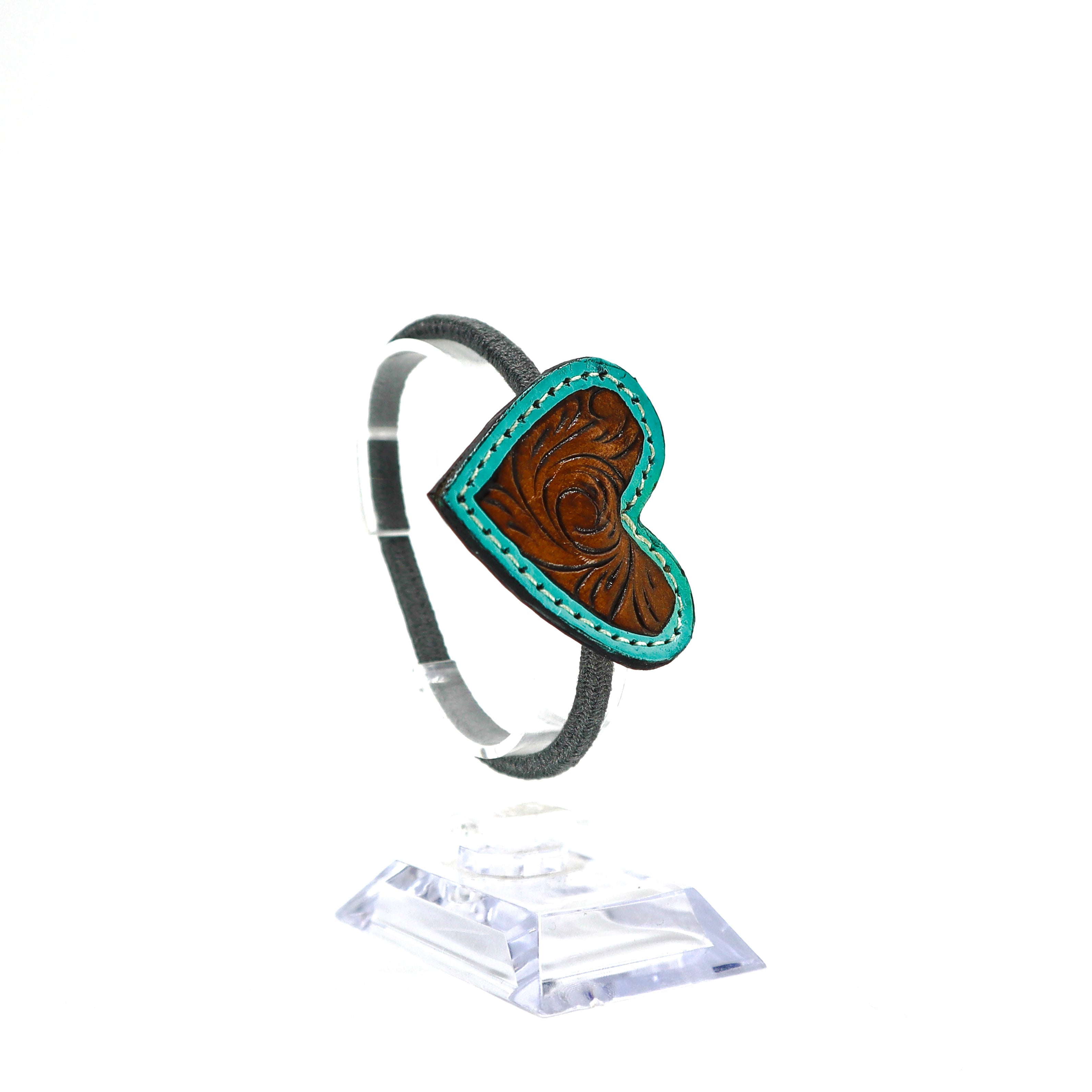 Handmade leather heart ponytail holder with hand-carved design and pink stitching