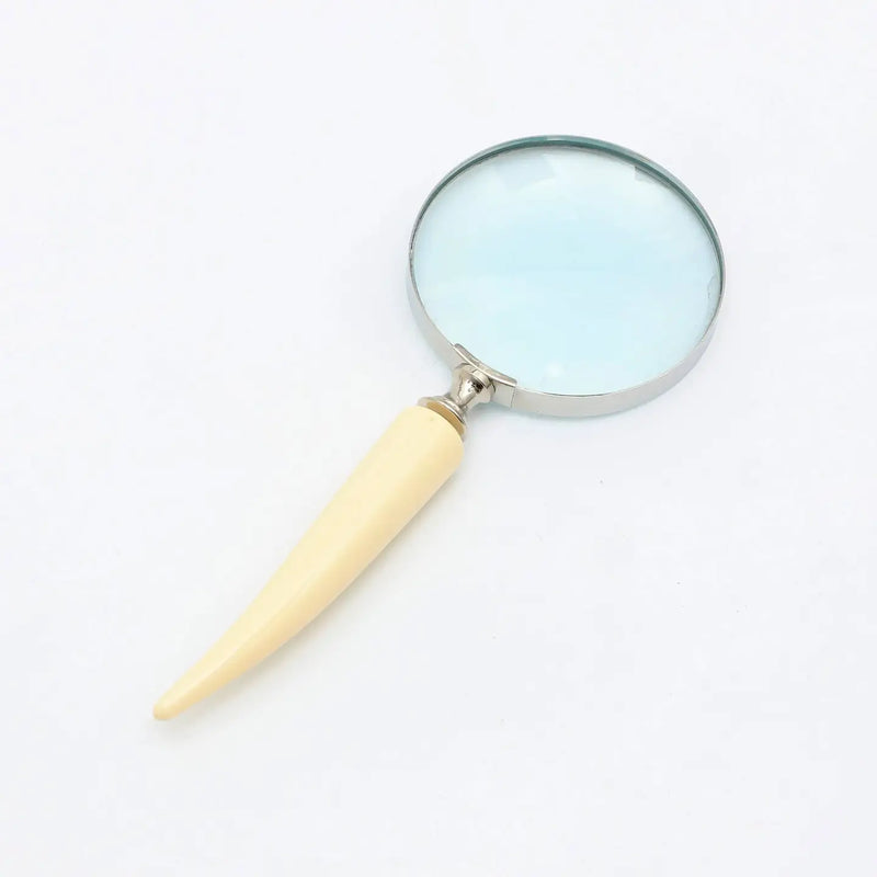 Decorative magnifying glass with silver electroplated frame and ivory resin handle on white background