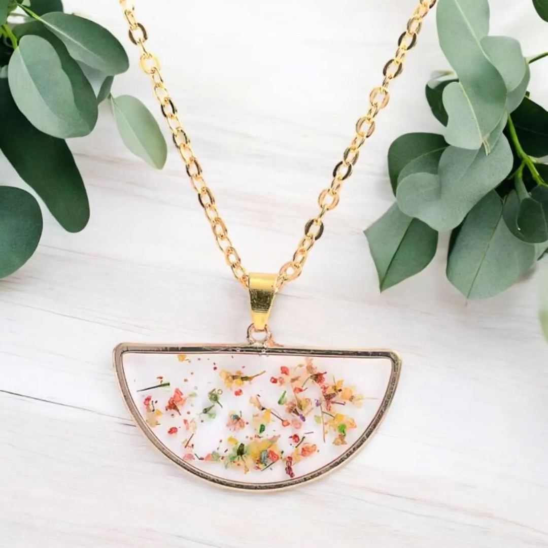 Transparent floral pendant necklace with real dried flowers encased in clear resin and a golden chain